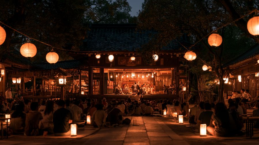 夜の境内で石見神楽の舞台を鑑賞する観客席の様子。提灯の光が優しく照らす